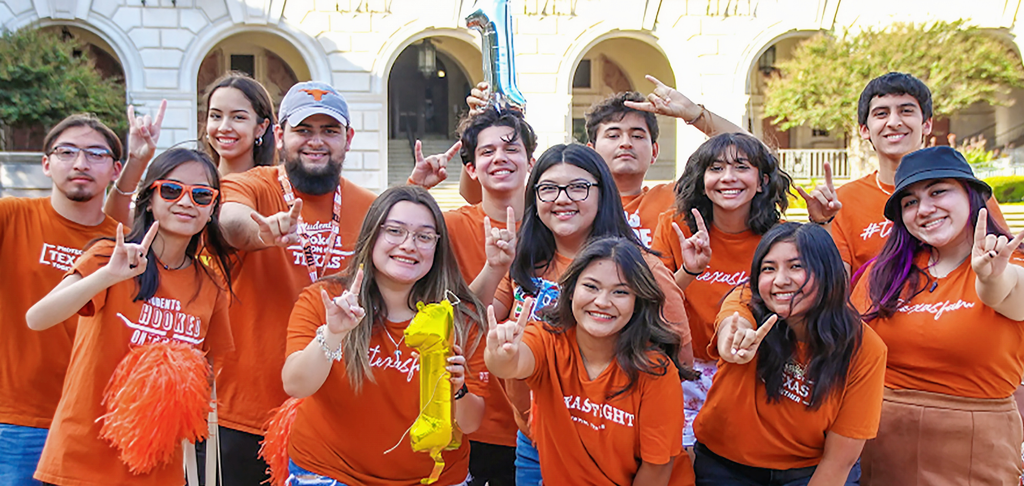 First Gen Students Gathered Together Wearing Orange and Each Making the Longhorn Gesture