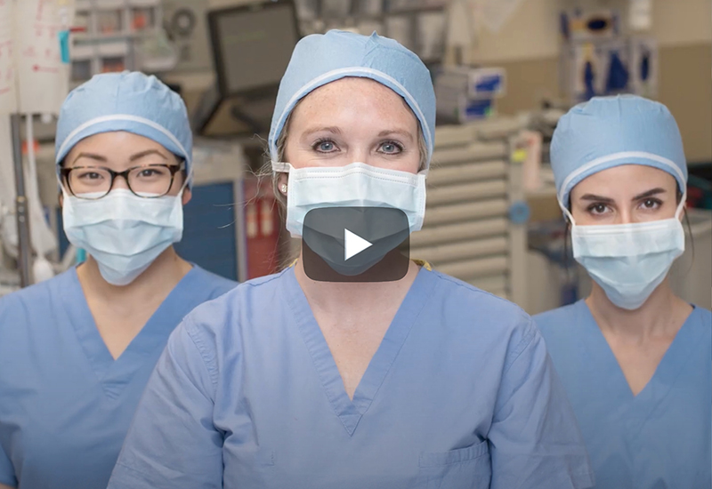 Three healthcare workers wearing scrubs and surgical masks.