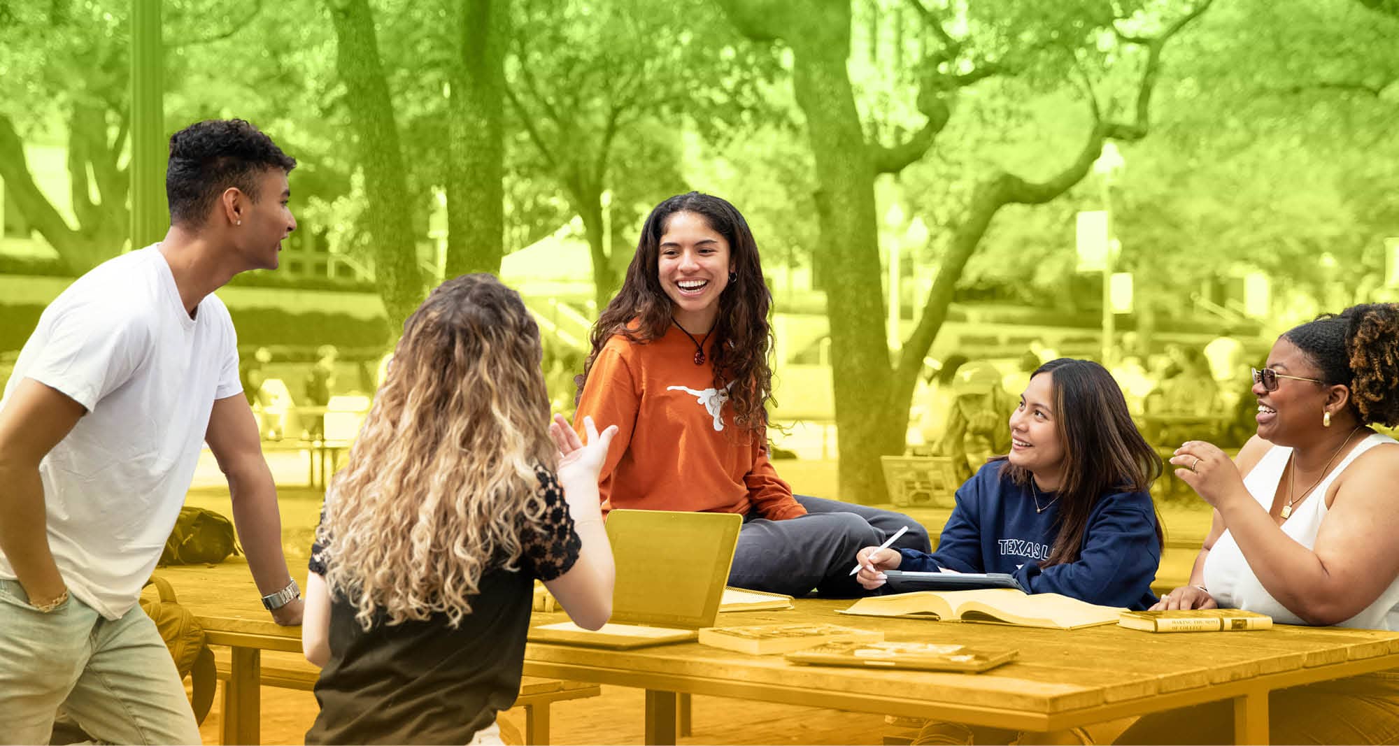 5 UT Austin students outside, talking at a table