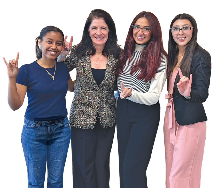 Kelly Steckelberg and students gesturing Hook'em Horns.