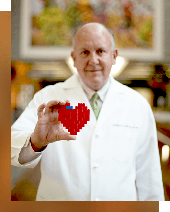 Dr. Fraser holding a pixelated heart art piece.